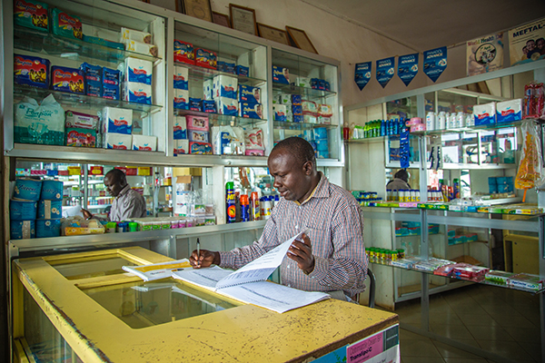 man reading paperwork at counter in Tanzania pharmacy