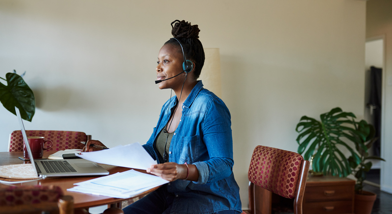 african american woman wearing headset at home on laptop