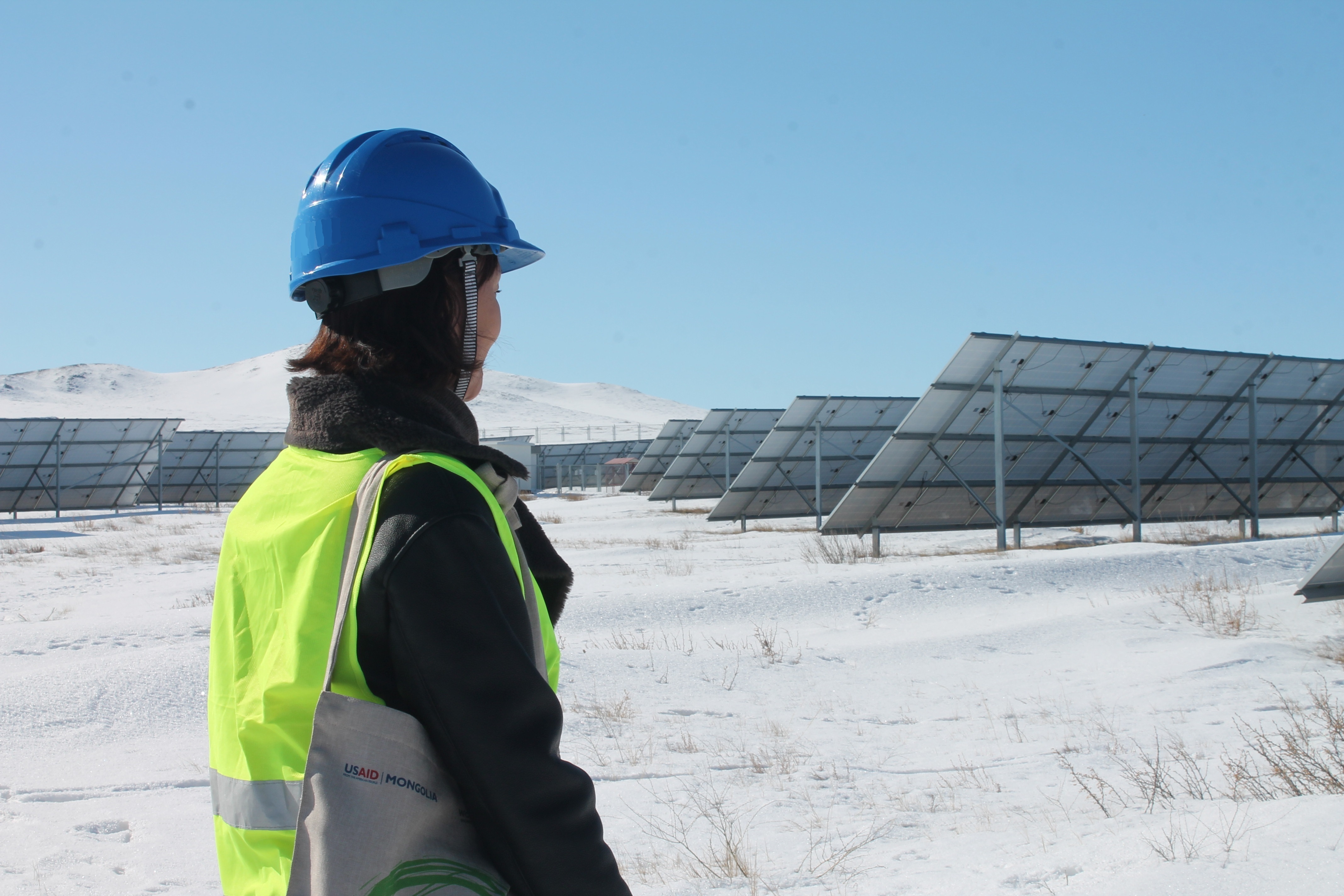 woman in snow field next to solar panel farm