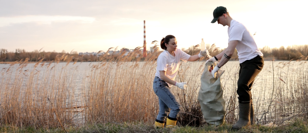Man and woman cleaning up trash next to a river
