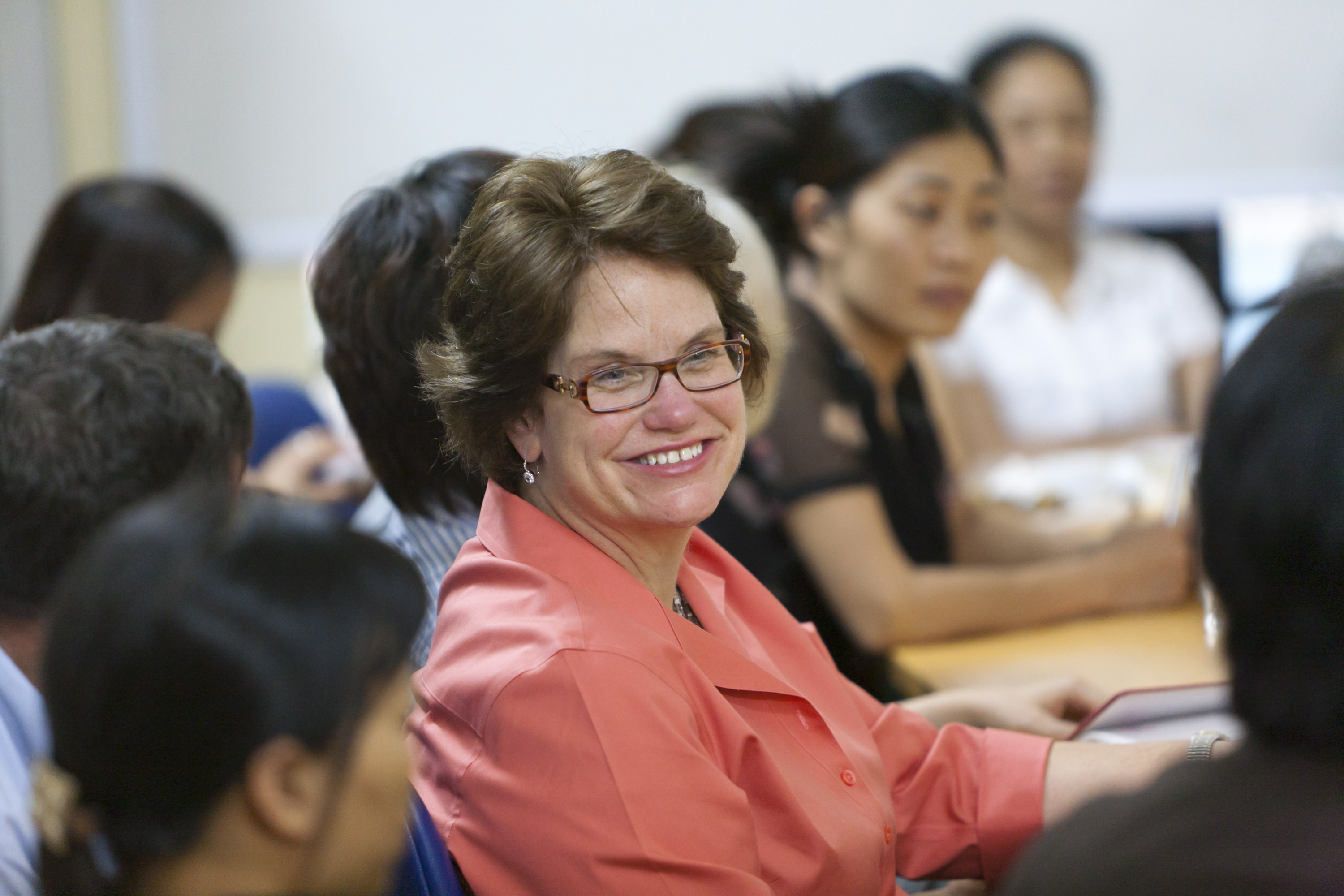 Abt CEO Kathleen Flanagan smiling and sitting with people