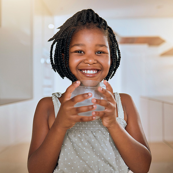 Young girl holding glass of water smiling
