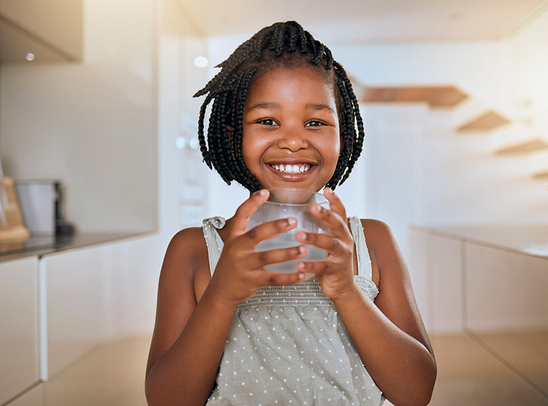 Young girl holding glass of water smiling