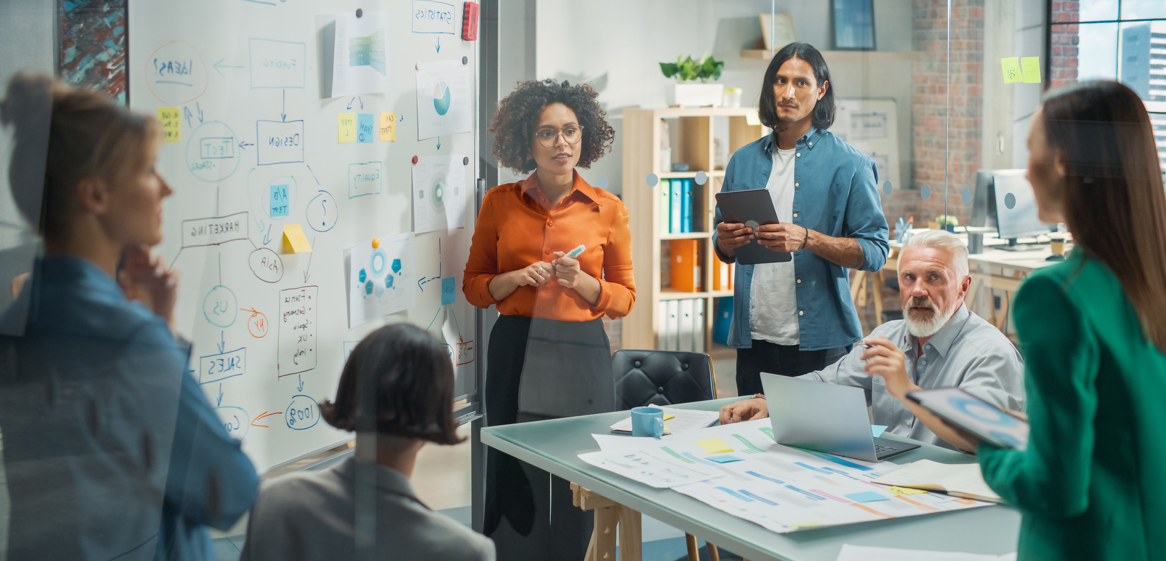 Black Female leader Uses Whiteboard with Data, Statistics, Discusses Strategy with colleagues