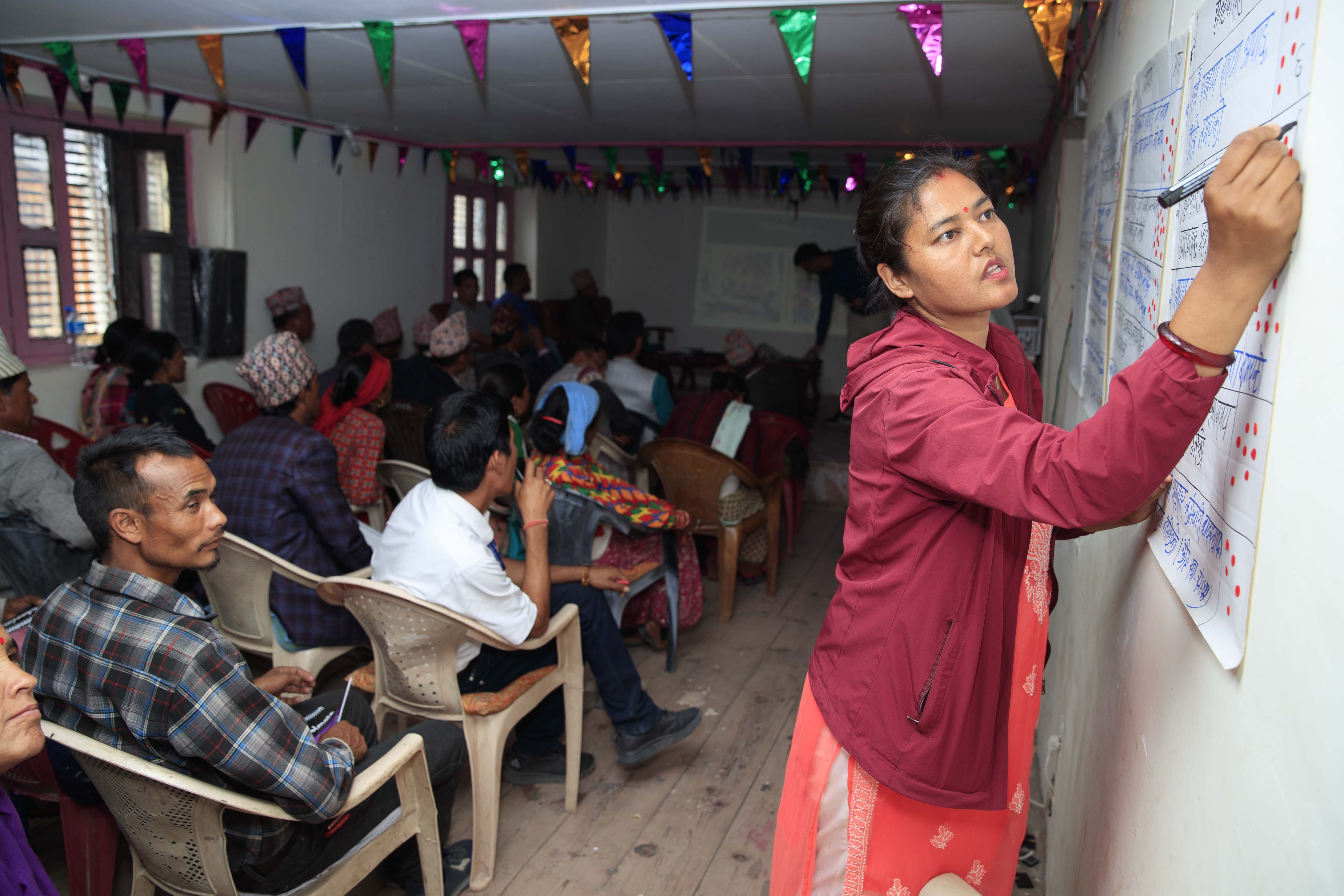 Woman in Nepal writing on a chart in a classroom
