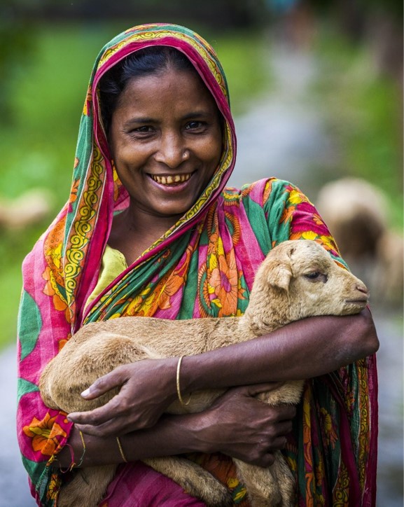 smiling bangladeshi woman holding a baby goat