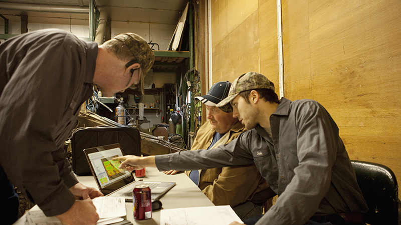 farmers gathered around a laptop