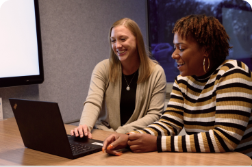 two abt employees talking as they look at a laptop together