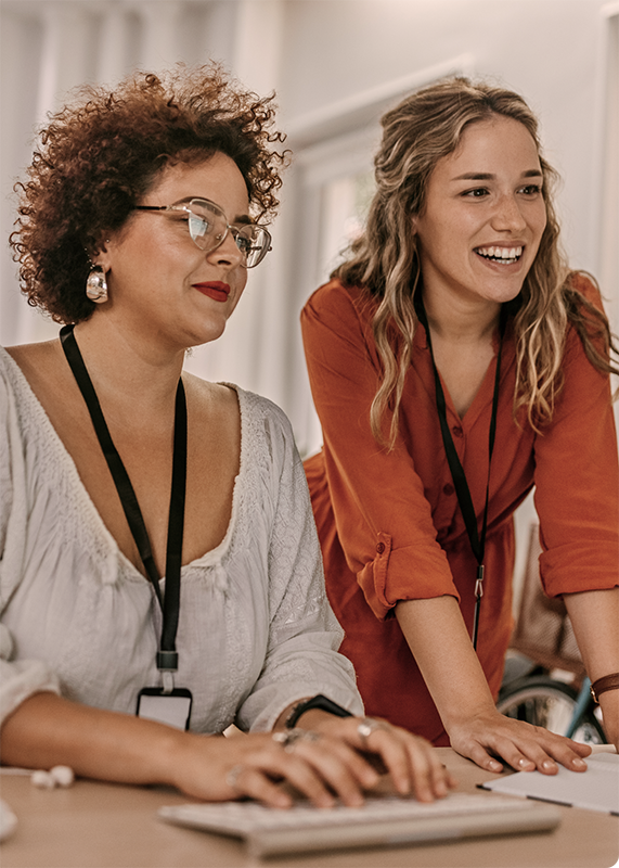 Two women review content on a computer monitor.