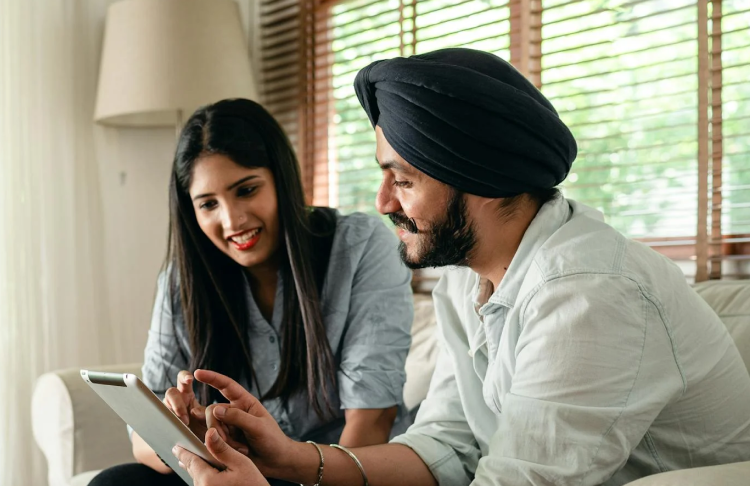 An east asian couple smiling as they use a mobile tablet.