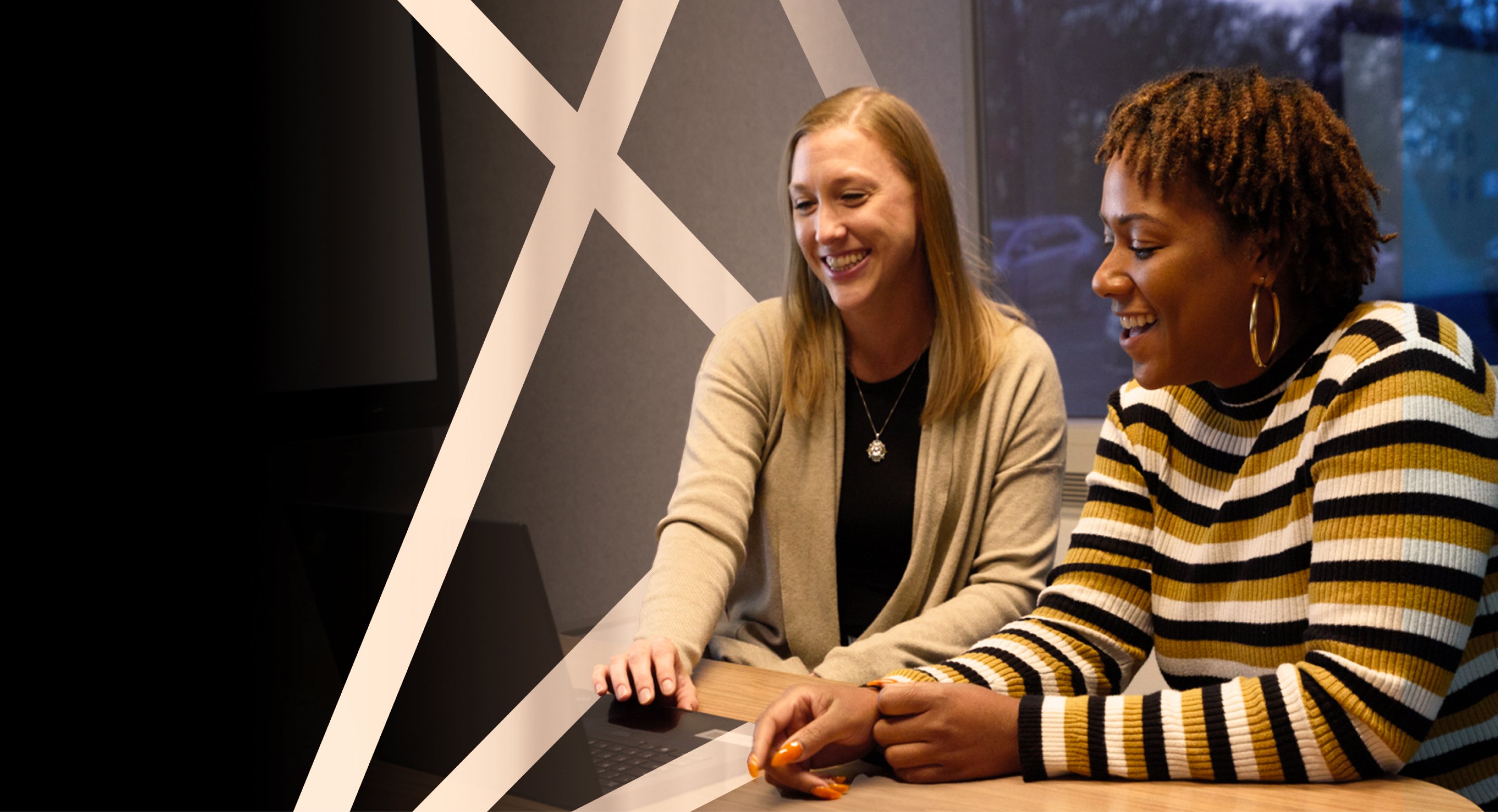 two abt staff smiling in front of a laptop