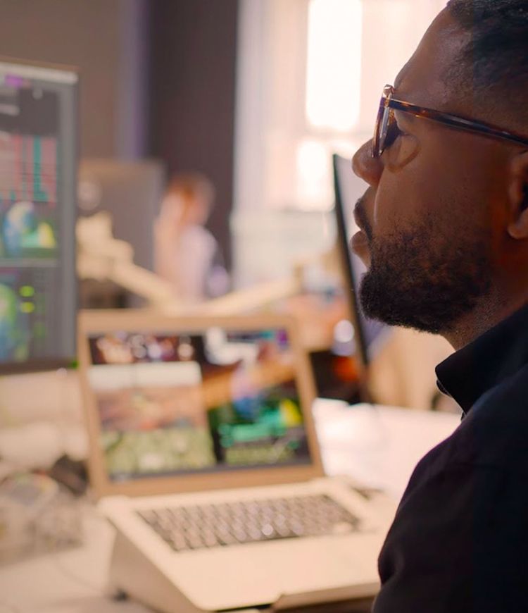 Man looking at a computer monitor showing images of globes and charts of data.