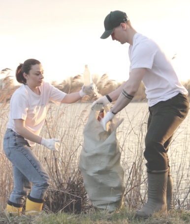 Man and woman cleaning up trash next to a river