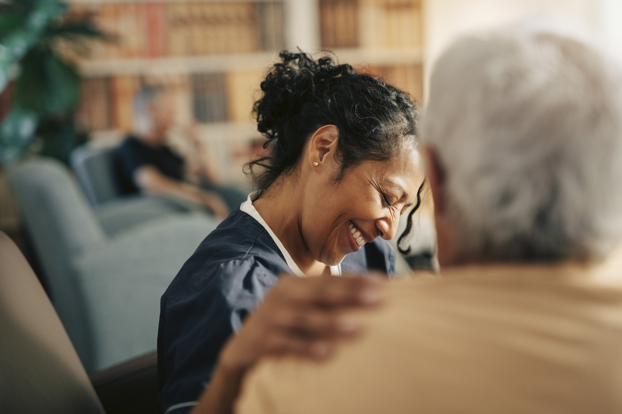 Smiling female nursing assistant with hand on shoulder of senior patient at retirement home