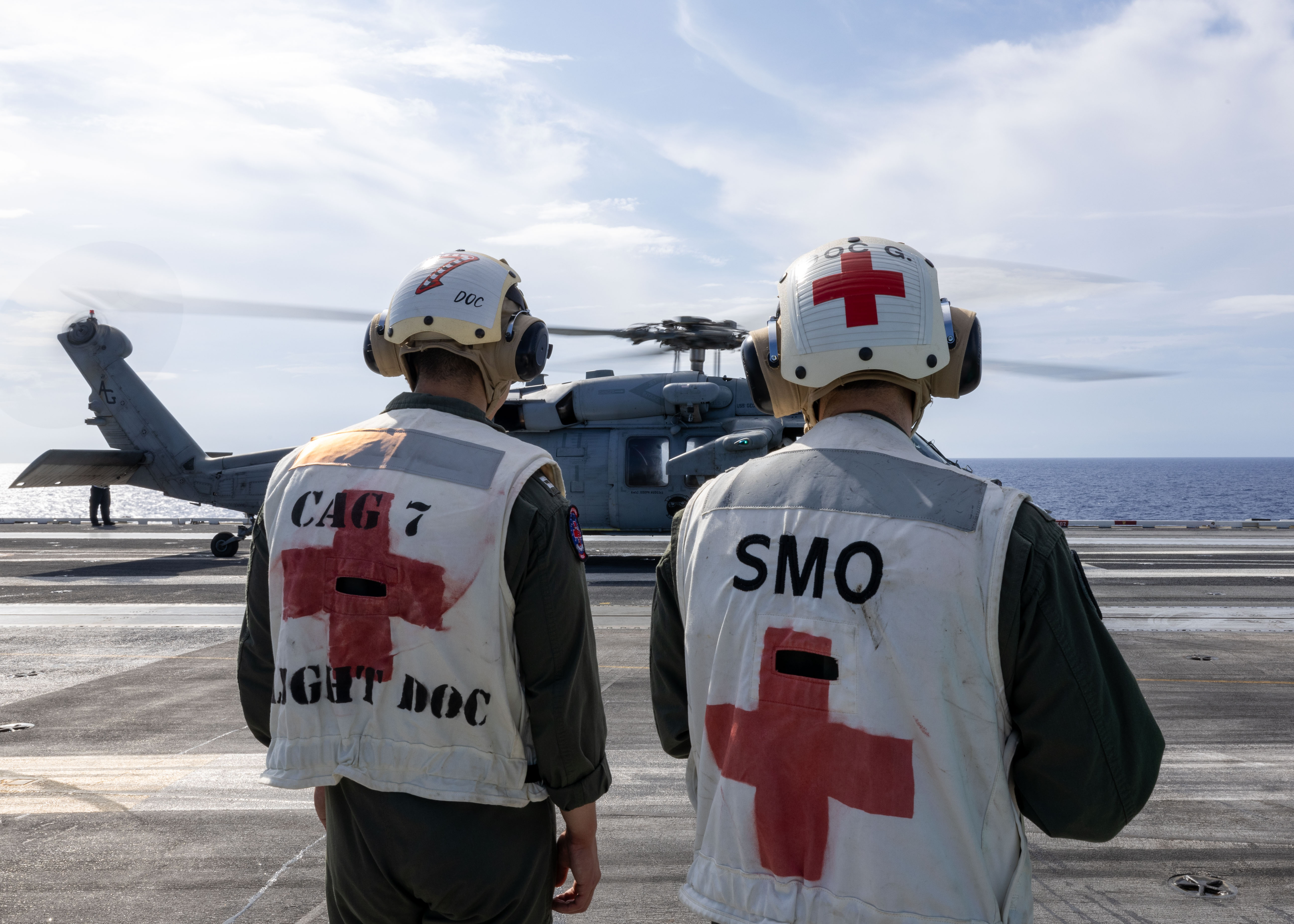 military medical personel standing near helicopter on an aircraft carrier