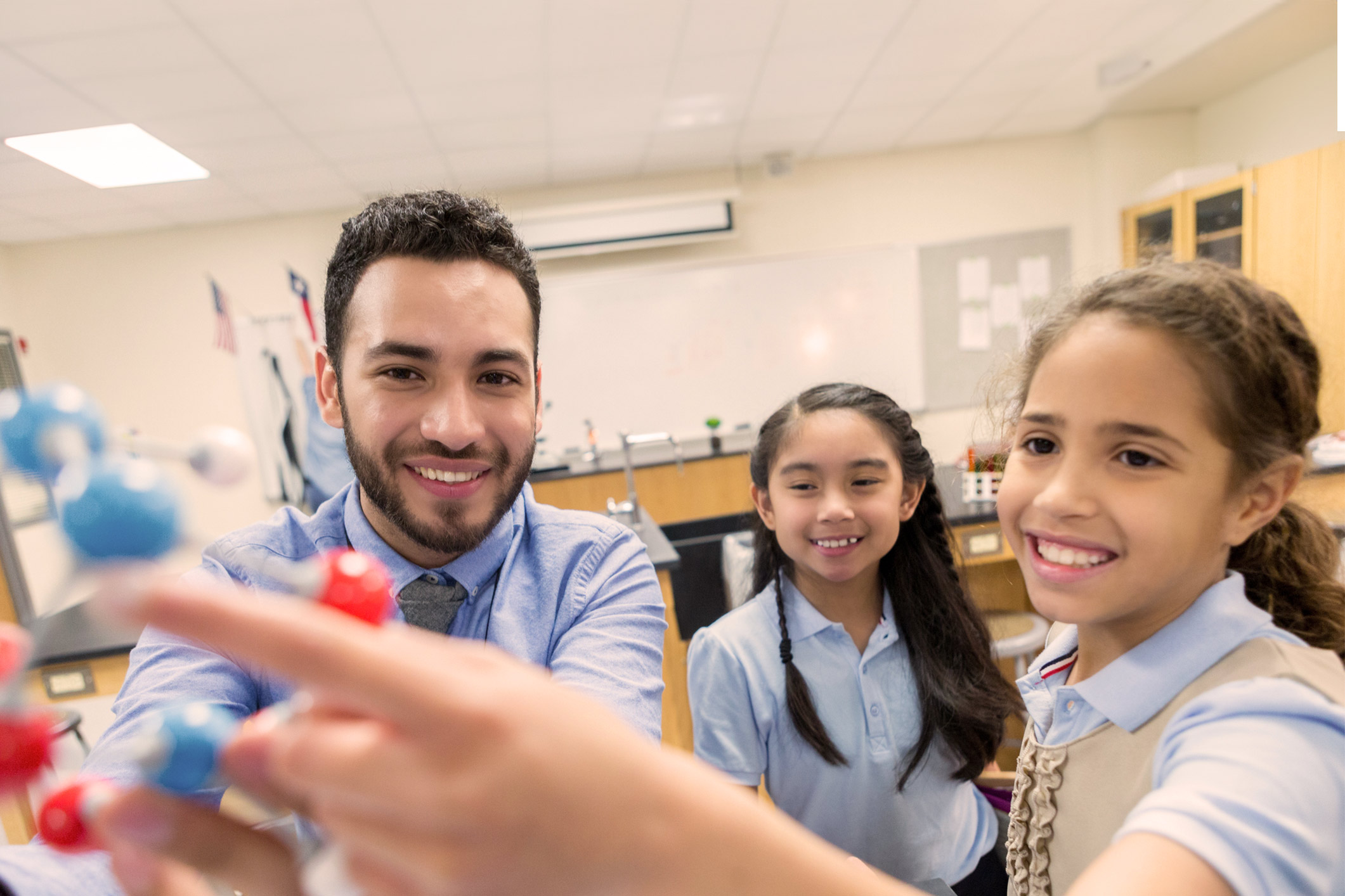 a teacher showing smiling students a molecule model