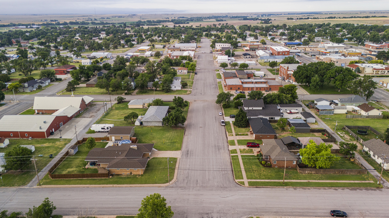 Main street stretching along rural residential neighborhood of Garden City, Kansas. Vast farmlands nestled in the distance