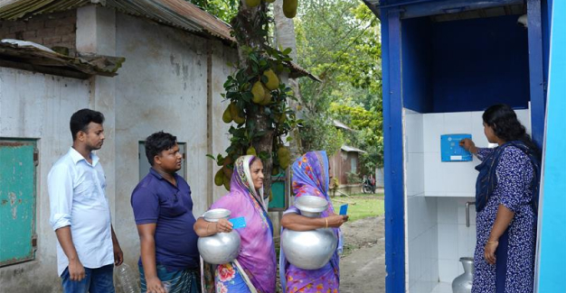 people in line next to water purification station in bangladesh