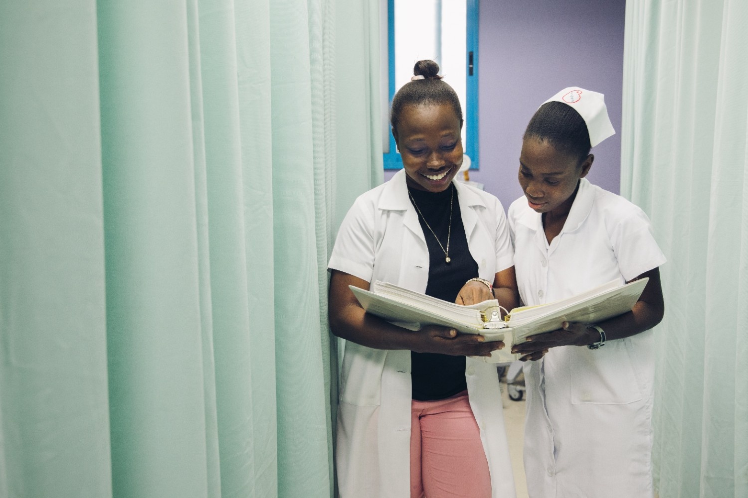 two Haitian medical professionals smiling and talking