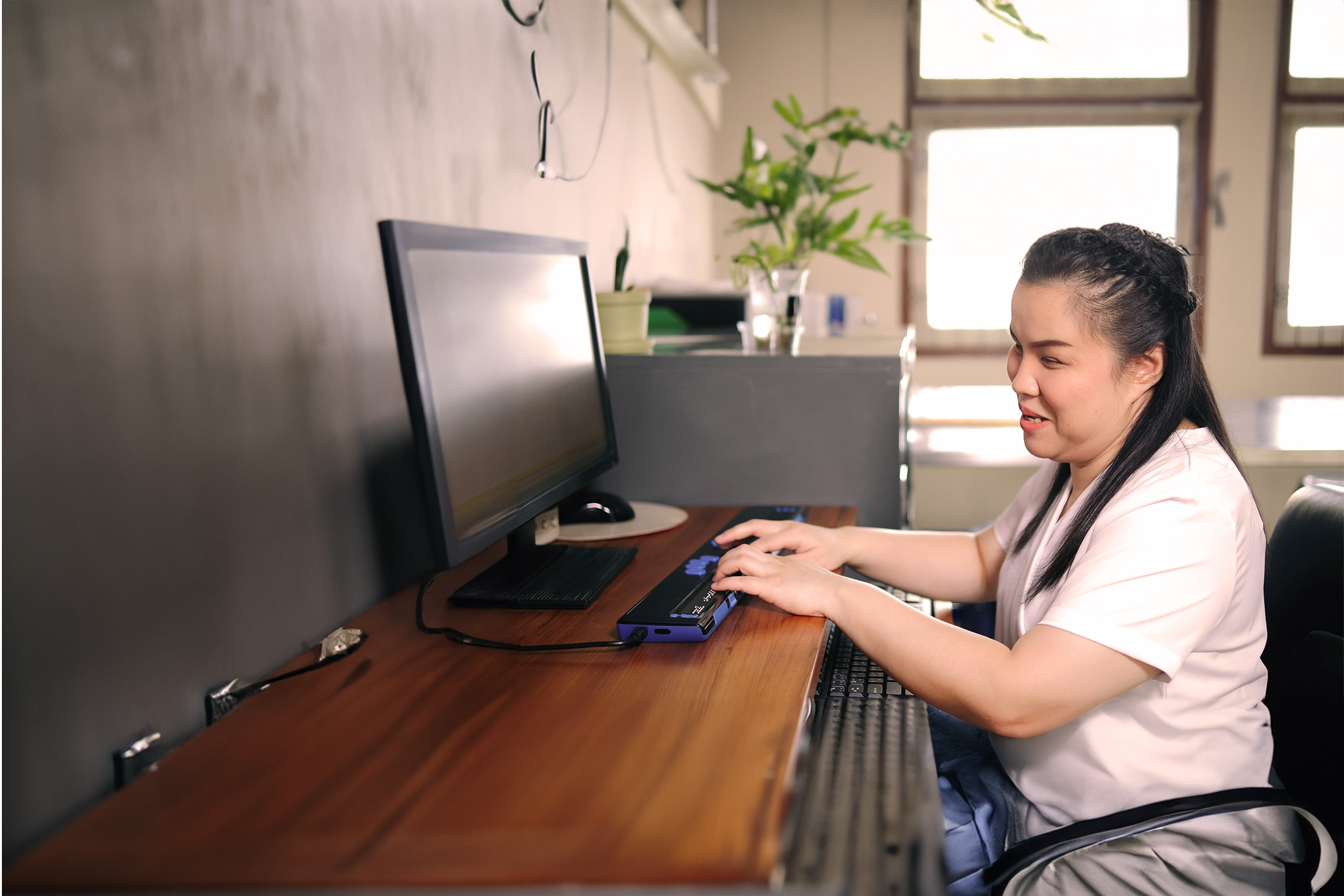 woman with a disability smiling and working at a computer