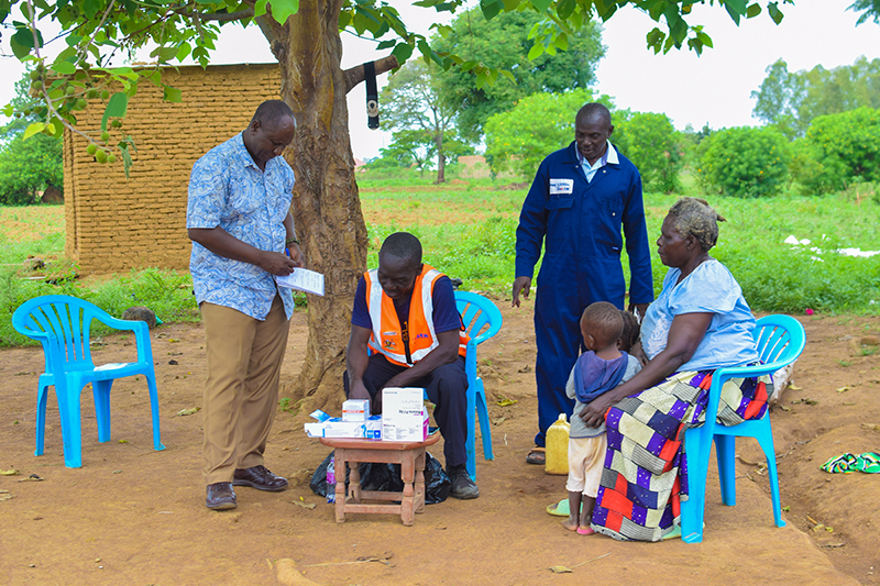 PMI evolve workers in a village in uganda talking with locals and distributing medication