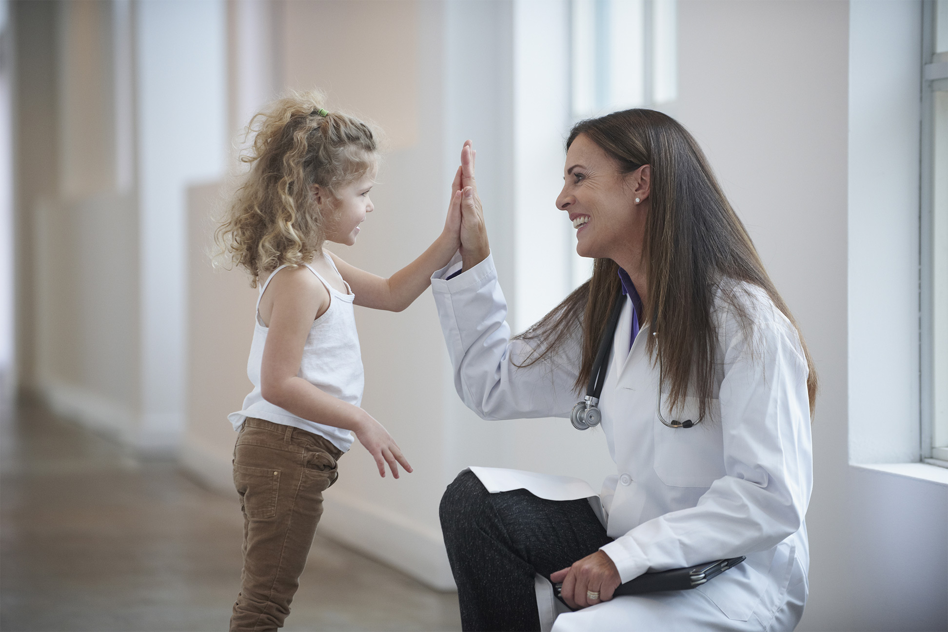 doctor high-fiving a smiling young girl
