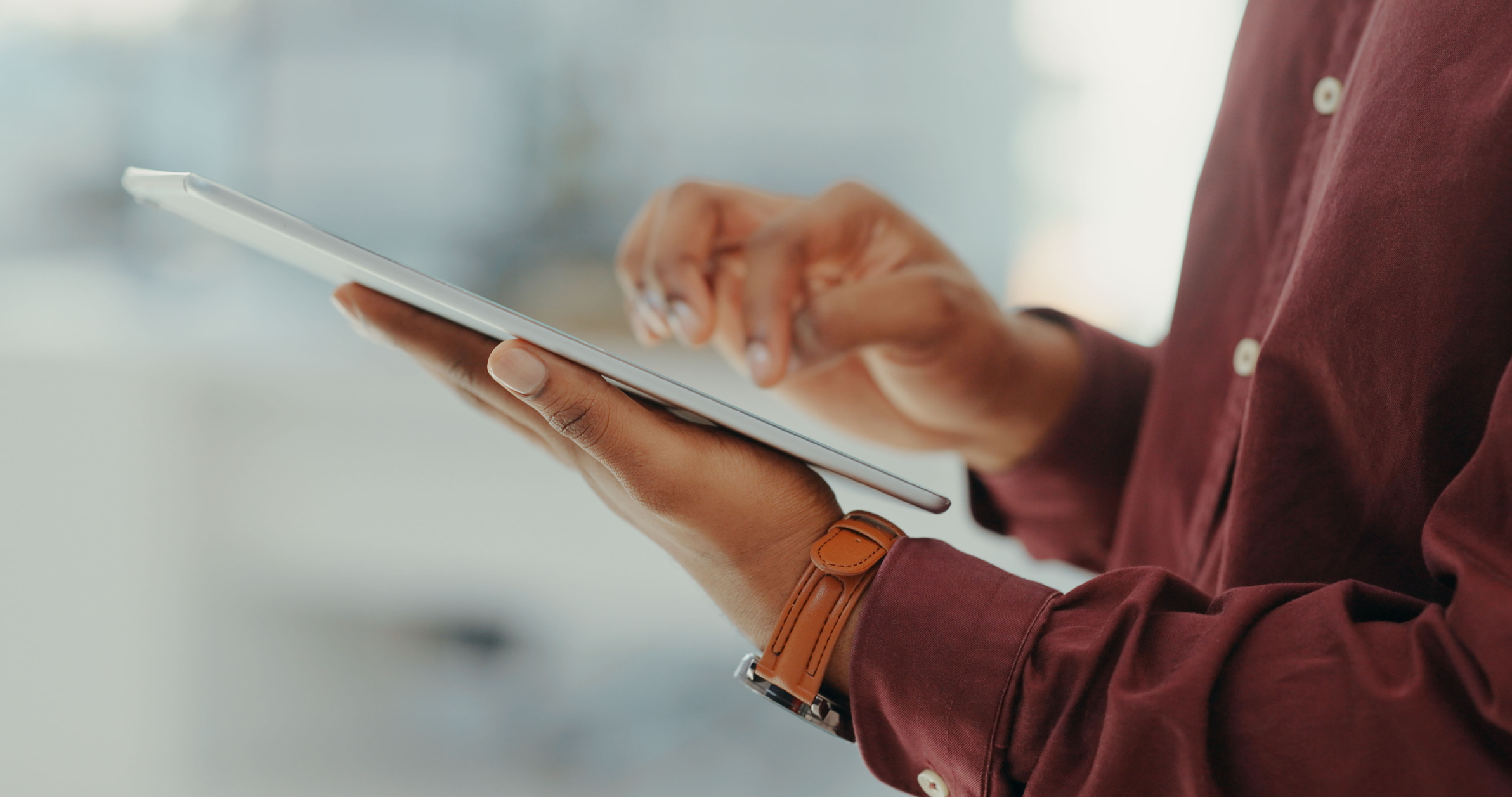 POC woman's hands holding and typing on a tablet device