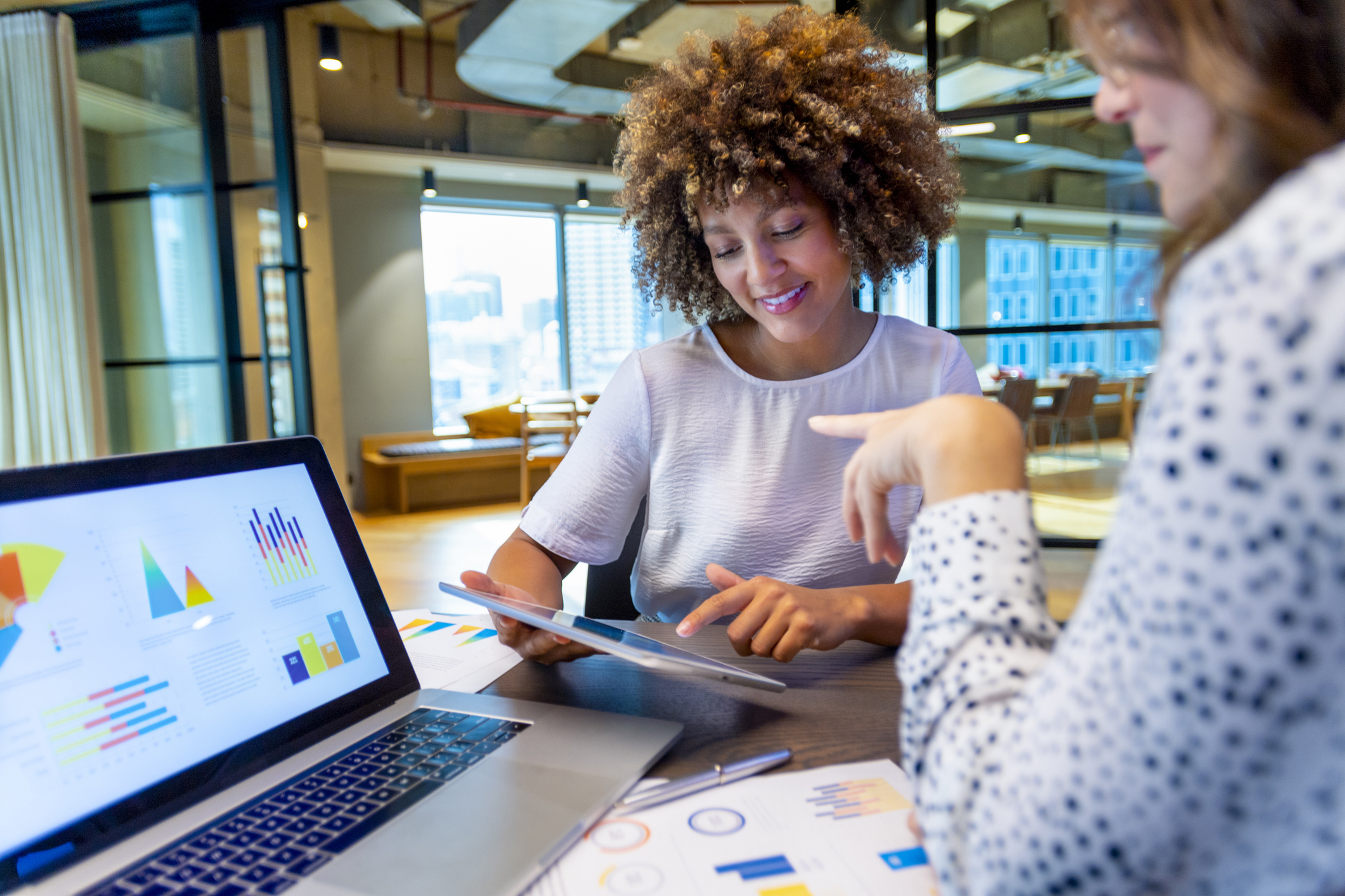 two women colleagues discussing data over a laptop and tablet