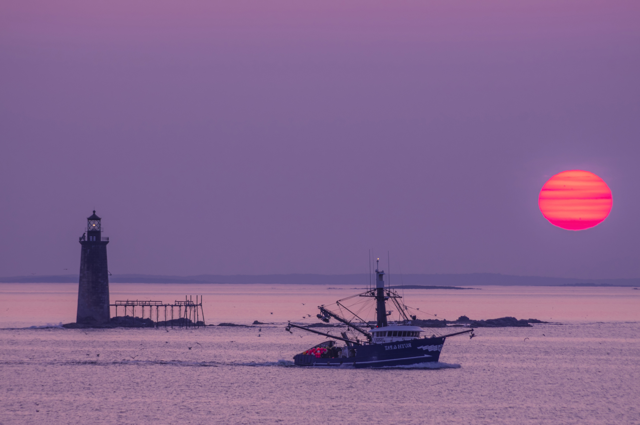 cape elizabeth maine fishing boat and lighthouse at sunset
