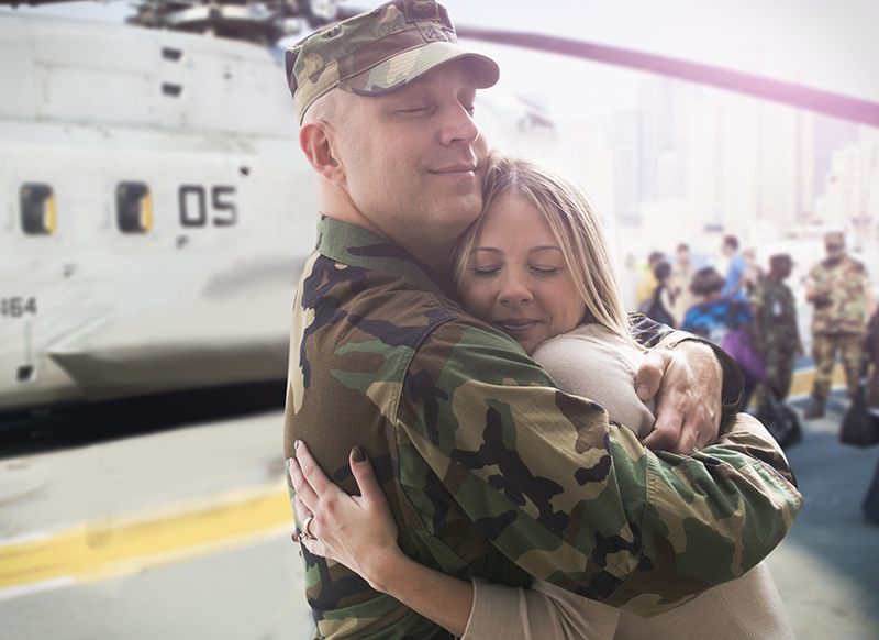 soldier hugging his wife next to military helicopter