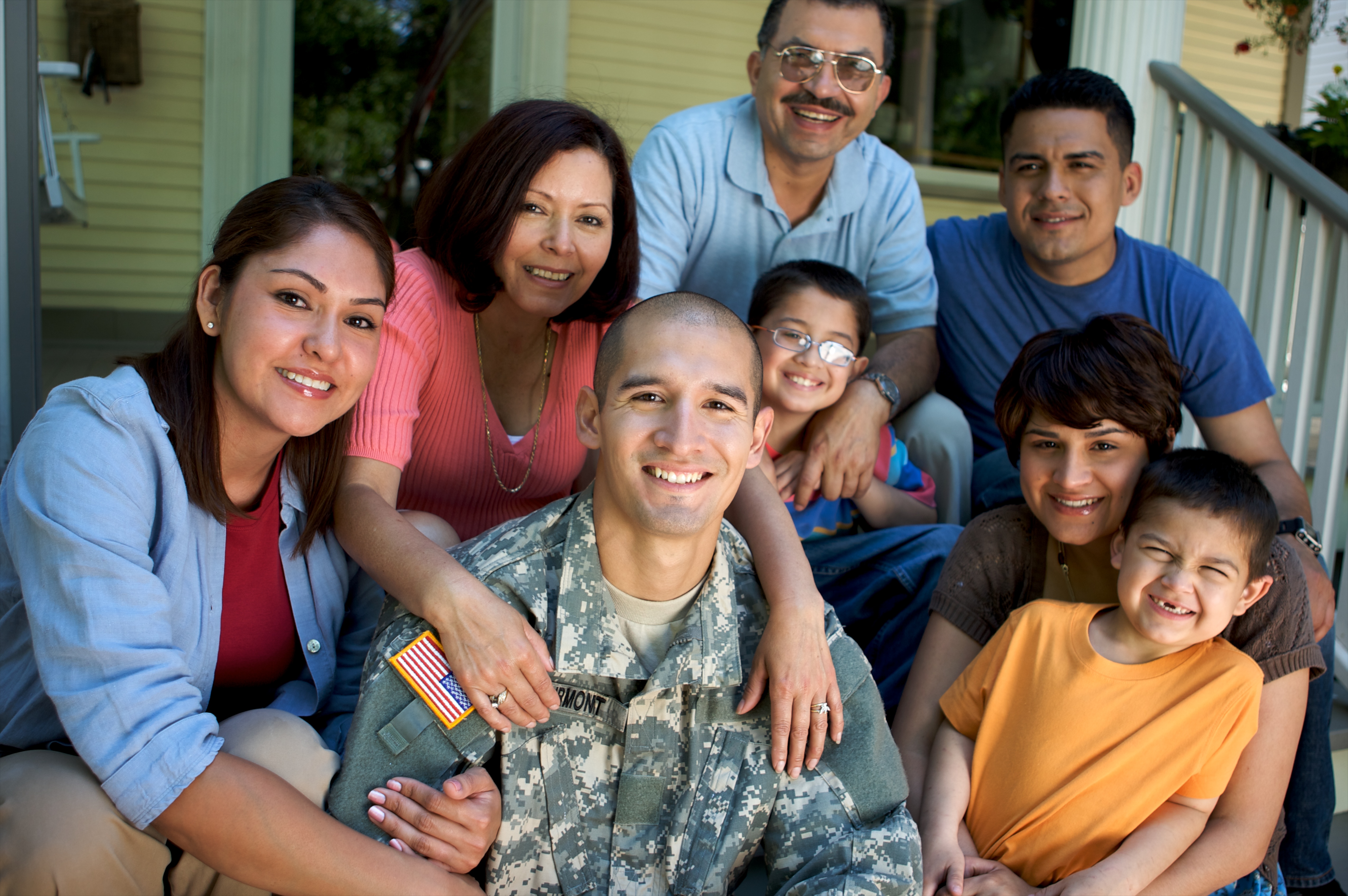 portrait showing a smiling soldier on house steps surrounded by his happy family