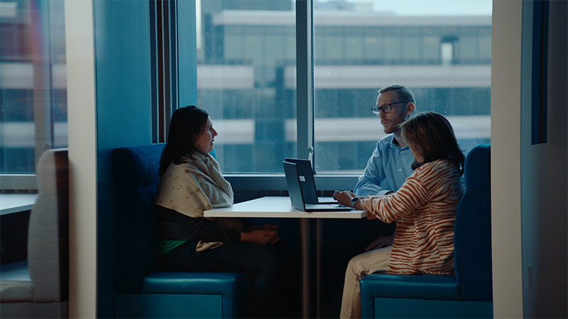 three colleagues talking in booth