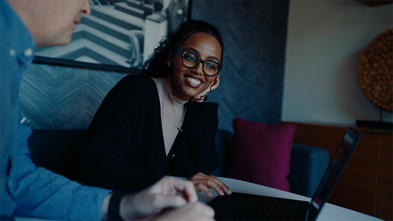 woman person of color smiling with a colleague