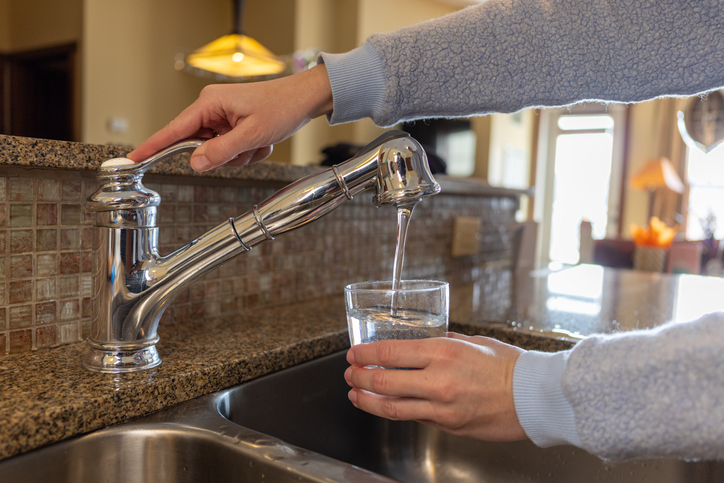 A woman fills a cup of water at a tap