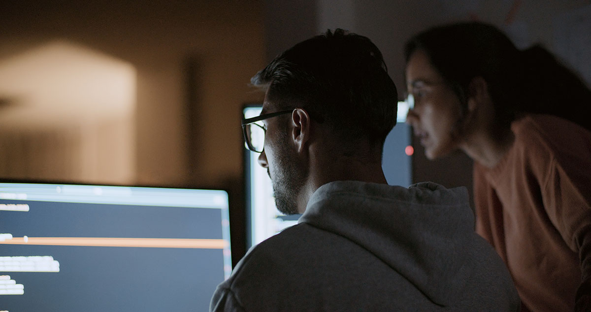 artistic image of two people leaning over a glowing computer screen