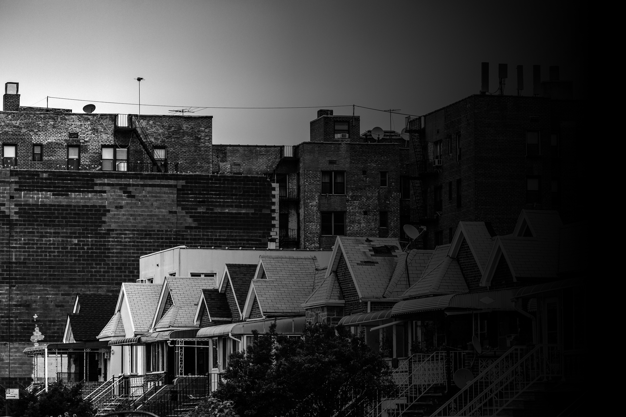 Rows of small houses in front of larger brick buildings in urban setting