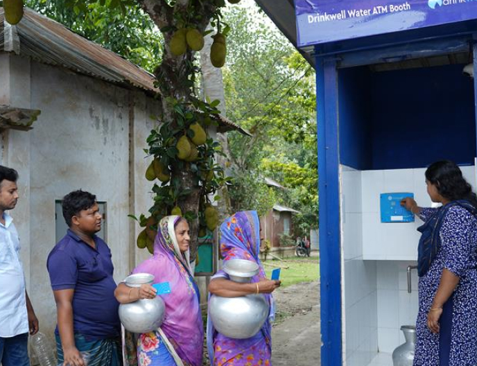 Bangladeshi men and women line up to get clean drinking water from a DrinkWell ATM Booth