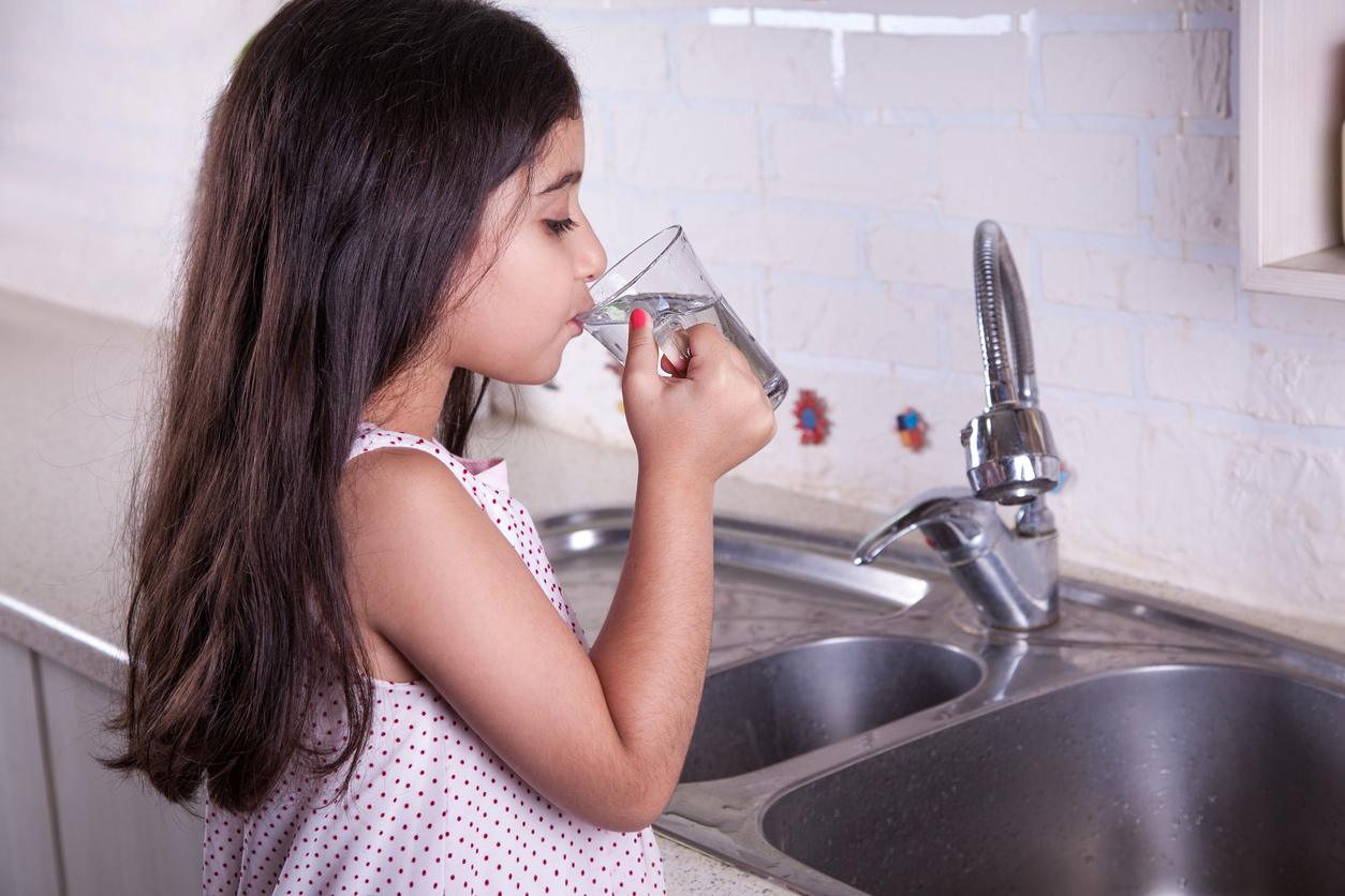 girl drinking water at sink