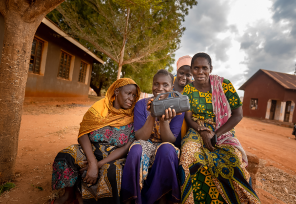 women with a handheld radio in a village in Tanzania
