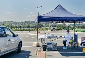 car parked next to covid testing station set up in a parking lot