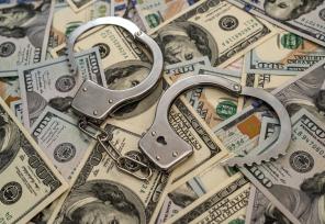 artistic image of handcuffs lying on top of a pile of 100 dollar bills