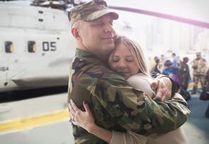 soldier hugging his wife next to military helicopter