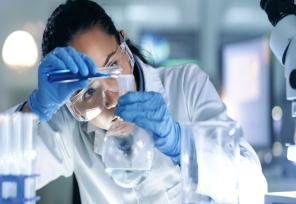 woman scientist looking closely as she pours a liquid into a beaker
