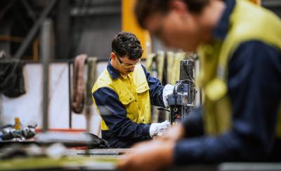 Qualified welders working on steel construction, grinding and welding iron parts in modern bright warehouse