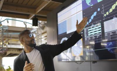 man conducting a seminar / lecture with the aid of a large screen
