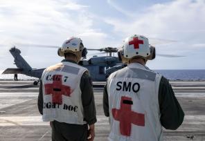 military medical personel standing near helicopter on an aircraft carrier
