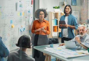 Black Female leader Uses Whiteboard with Data, Statistics, Discusses Strategy with colleagues