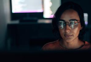 artistic photo of a computer screen reflected in a woman's glasses 