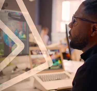 Man looking at a computer monitor showing images of globes and charts of data.