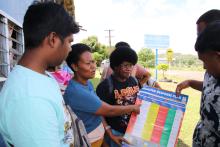 Woman in Fiji pointing to a chart labeled 'Disaster Response Plan'
